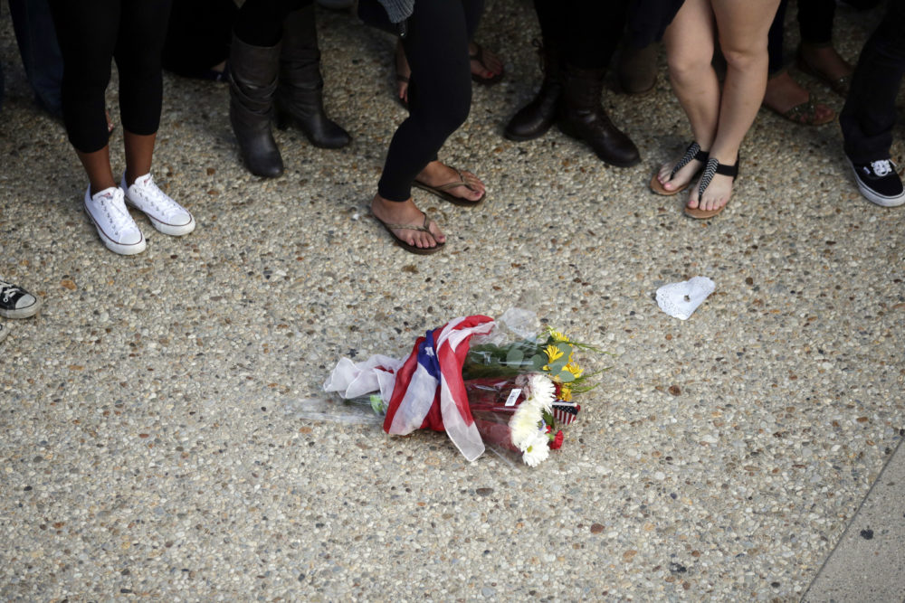 In this May 24, 2014 file photo, students stand next to a bouquet of flowers during a vigil held to honor the victims a mass killing at University of California, Santa Barbara. The shooter, Elliot Rodger, was said to have had hostility towards women. (Jae C. Hong/AP)
