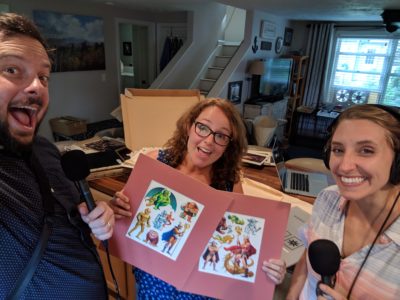 Ben (left), Linda Petrucci (middle), and Amory (right) posing with the original designs for the Land of Ta sticker sheets (Ben Brock Johnson/WBUR)