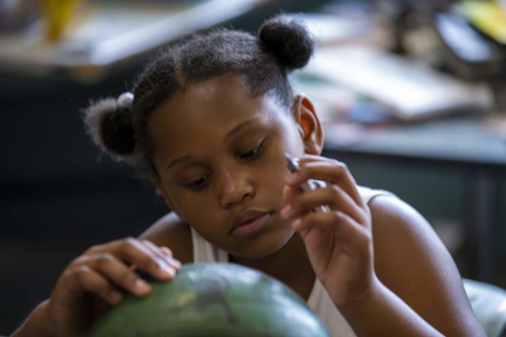 8-year-old Za'nii Morris decorates an old basketball at the Yawkey Boys and Girls Club in Roxbury. The basketballs are being collected by artist Shaka Dendy to use to create a large scale public sculpture which will be on display at the Boston Center for the Arts Plaza on Tremont St. (Jesse Costa/WBUR)