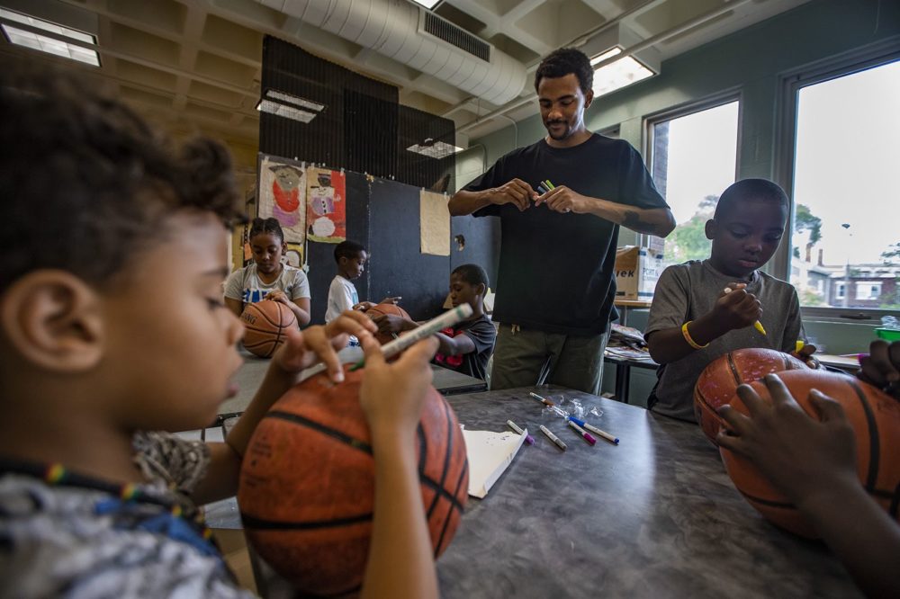 Artist Shaka Dendy prepares markers for a group of 8- and 9-year-old boys at the Yawkey Boys and Girls Club in Roxbury as they decorate old basketballs, which he will use to create a large scale public sculpture which will be on display at the Boston Center for the Arts. (Jesse Costa/WBUR)