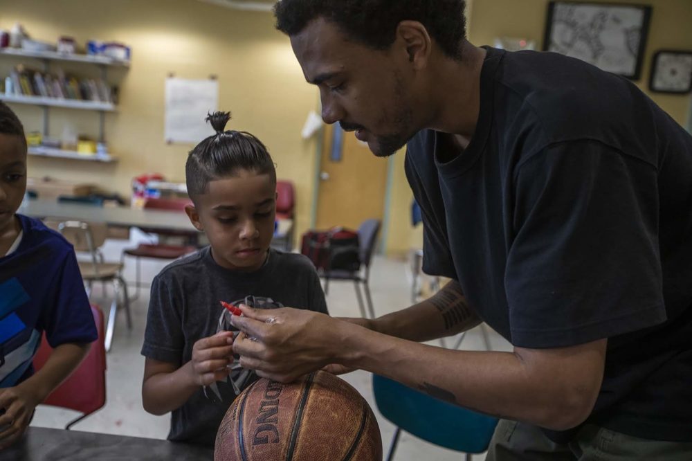 Artist Shaka Dendy prepares markers for a group of 8 and 9-year-old boys at the Yawkey Boys and Girls Club in Roxbury as they decorate old basketballs, which he will use to create a large scale public sculpture which will be on display at the Boston Center for the Arts Plaza on Tremont St. (Jesse Costa/WBUR)