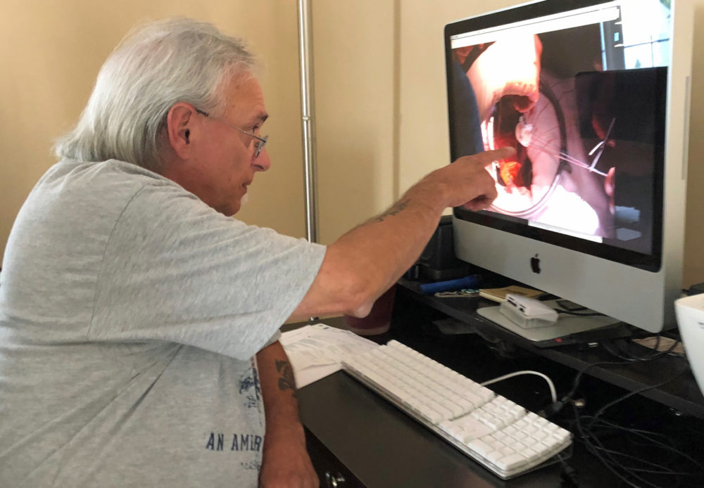 Photographer Dave Souza, at home in Dighton, looks at some of his favorite pictures from a 34-year career at the Herald News. He was laid off last week. (Callum Borchers/WBUR)