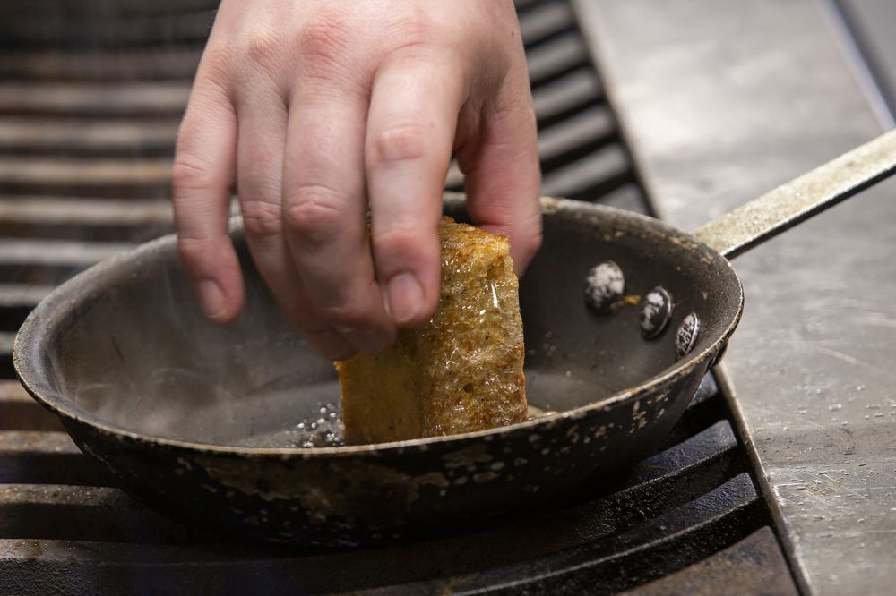 Chef Michael Morway grilling a piece of his Plimoth Cornbread, a part of a popular burrata dish on the Trillium menu. (Jesse Costa/WBUR)