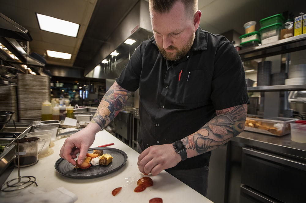 Chef Michael Morway assembling Burrata with pluots and Grilled Plimoth Cornbread in the kitchen at Trillium Brewing Fort Point. (Jesse Costa/WBUR)