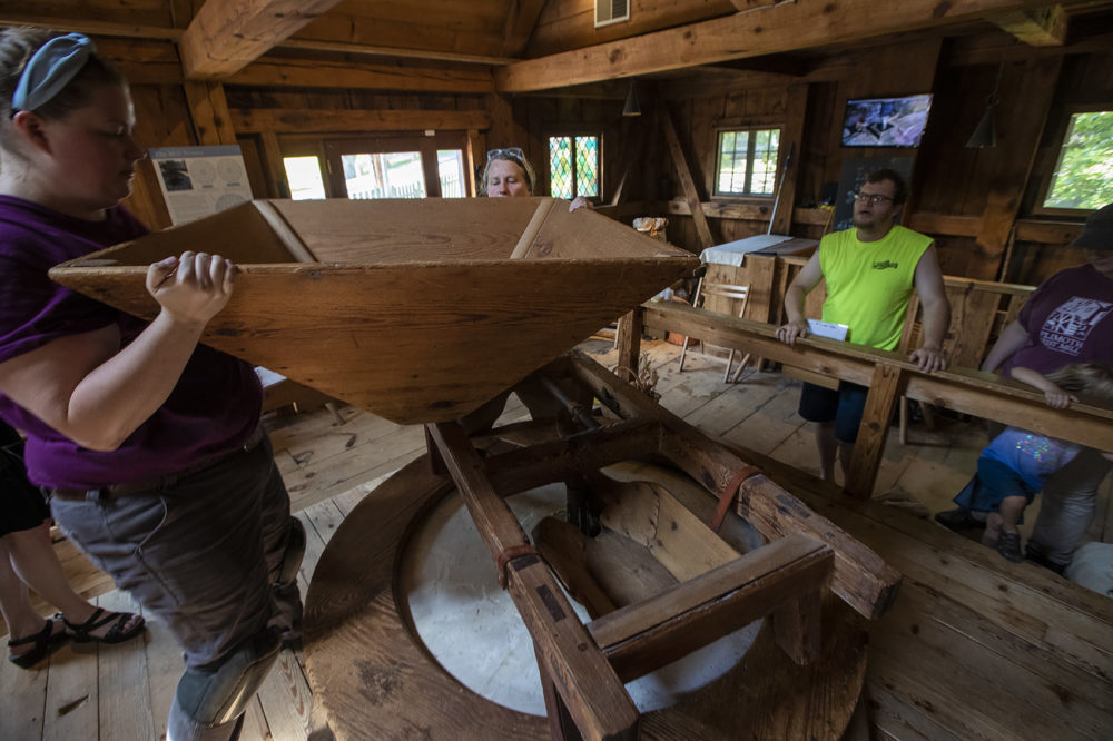 Kim VanWormer, right, and Sydney Tierney place the hopper into position as visitors watch from the side.. (Jesse Costa/WBUR)