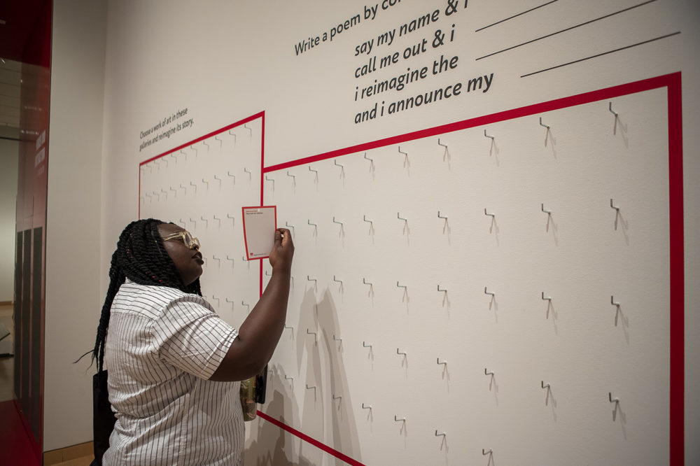 City of Boston Poet Laureate Porsha Olayiwola checks to see what the first response to an interactive exhibit encouraging visitors to complete a poem. (Jesse Costa/WBUR)