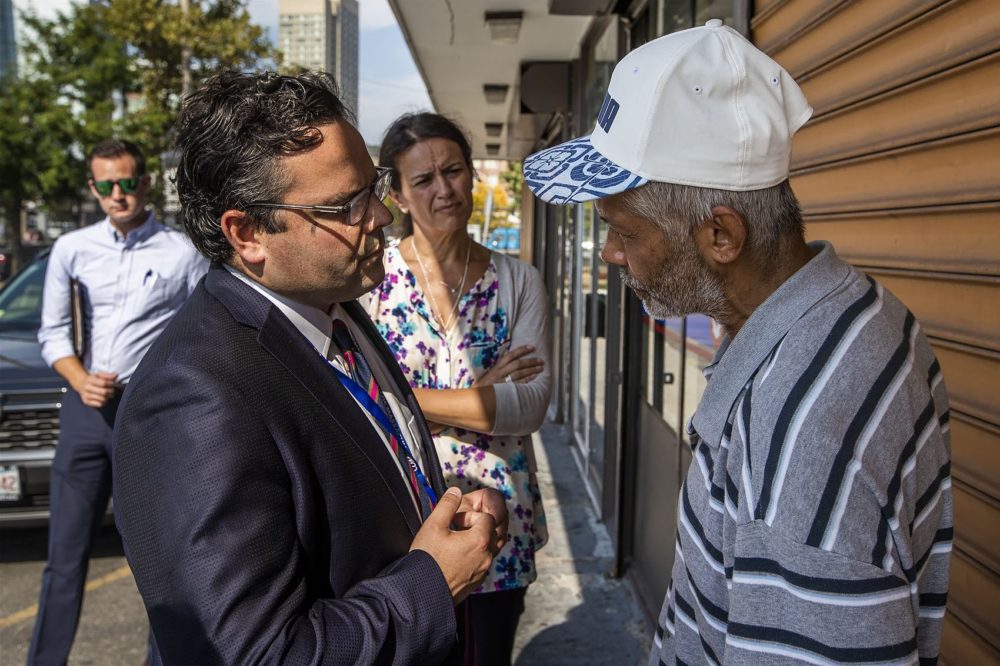 Collins and Essaibi George speak with Reuben in front of the Universal Church on Southampton Street. Reuben said he has been living on the streets and in various shelters in the area for the past three years. (Jesse Costa/WBUR)