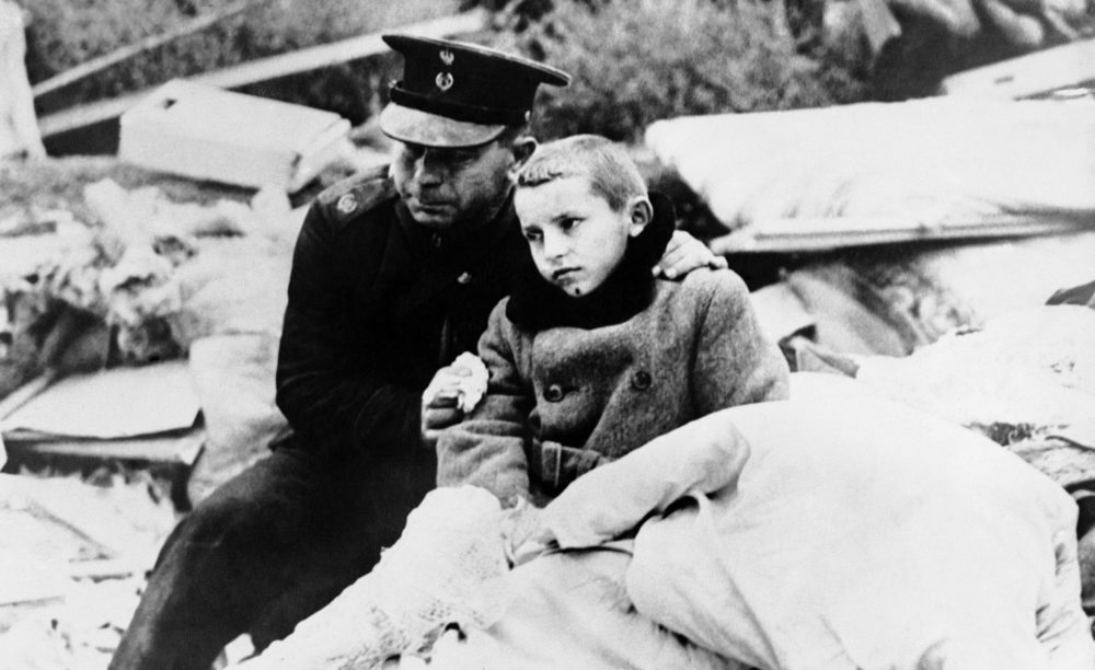 A uniformed Polish official comforts a boy whose mother was killed in an air raid on Warsaw, September 1939. The boy himself was in the wreckage for 12 hours before rescue crews liberated him. (AP file photo)