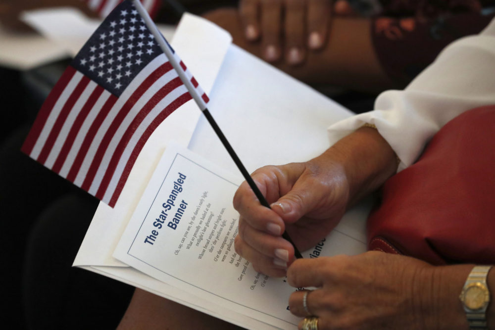 A citizen candidate holds an American flag and the words to The Star-Spangled Banner before the start of a naturalization ceremony at the U.S. Citizenship and Immigration Services Miami field office. (Wilfredo Lee/AP)