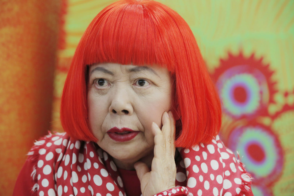Artist Yayoi Kusama, wearing a bright red wig and a Louis Vuitton polka dot scarf, speaks during an interview at her studio in Tokyo in 2012. (Itsuo Inouye/AP)