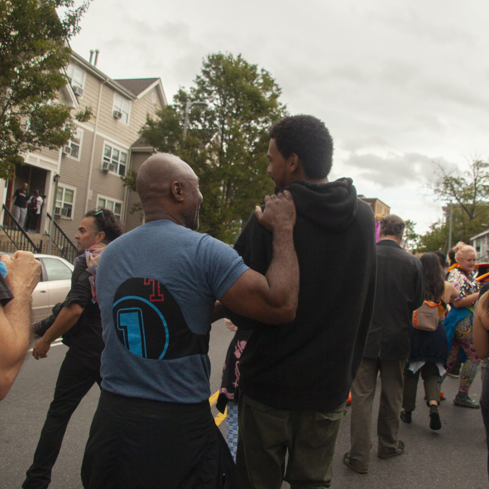 Nick Cave, on the left, shares a moment with Boston Center of the Art’s resident Shaka Dendy as they pass through Dendy's childhood neighborhood. (OJ Slaughter for WBUR) 