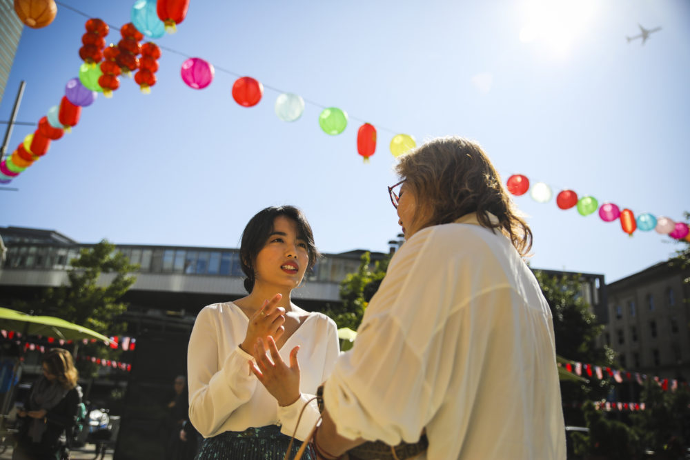 Rayna Yun Chou talks to a &quot;Concert for One&quot; guest in Chinatown. (Erin Clark for WBUR)