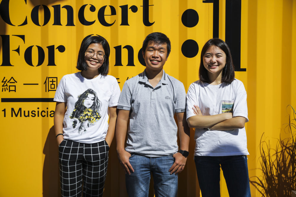 Boston Latin School students Mandy Sun, Eric Chan and Claire Ma stand in front of the shipping containers outfitted as mini-concert halls. (Erin Clark for WBUR)