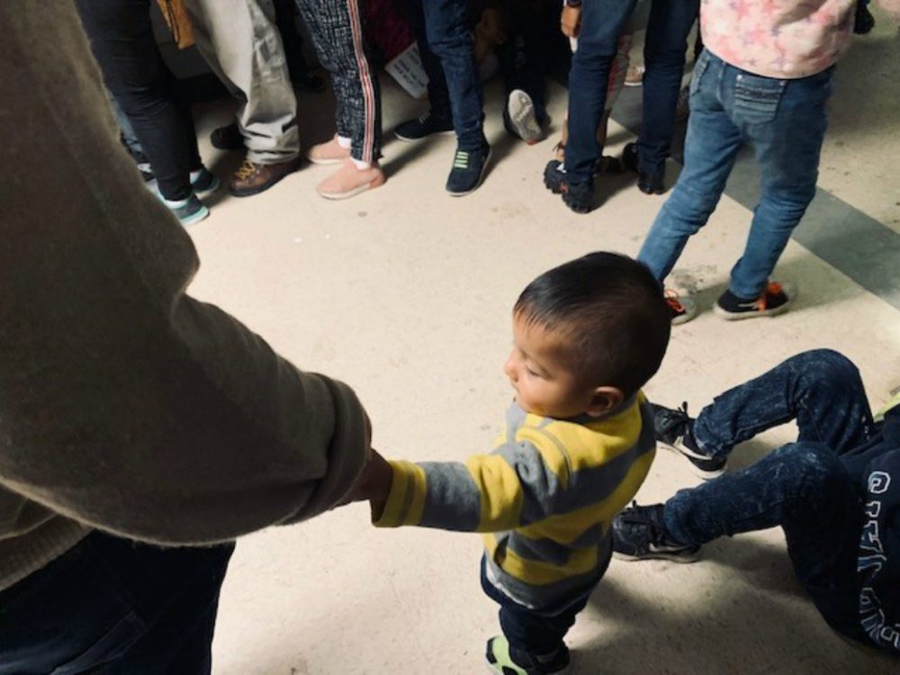 A little boy holds his father's hand at the Humanitarian Respite Center in McAllen, Texas.  The father and son are from Honduras. (Courtesy)