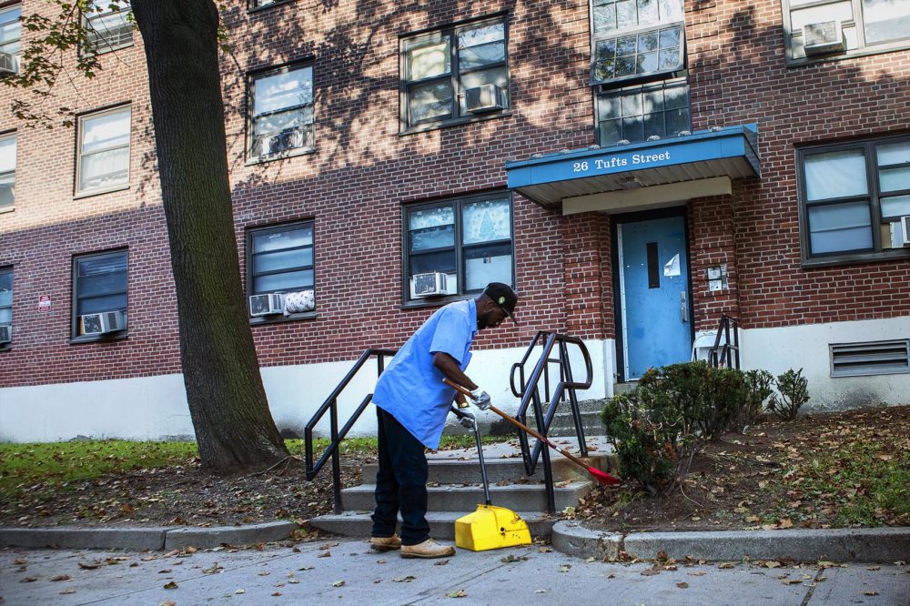 A worker cleans up around the Bunker Hill public housing complex on Tufts Street in Charlestown. (Jesse Costa/WBUR)