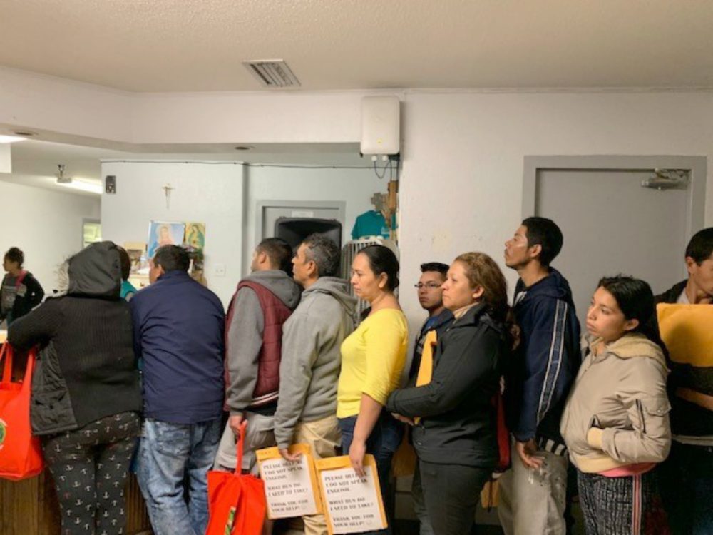 Migrants waiting in line to speak with family members via phone in the U.S. and gather bus information from volunteers at the Humanitarian Respite Center in McAllen, Texas. The average visit to the center is 24 hours. Migrants are given a hot meal, warm shower and a change of donated clothes and shoes. (Courtesy)