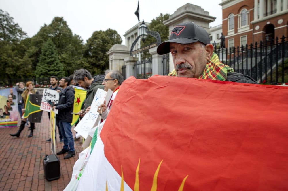 Agir Rojhat, of the New England Kurdish Association, holds up a flag of Kurdistan in front of the Massachusetts State House. (Robin Lubbock/WBUR)