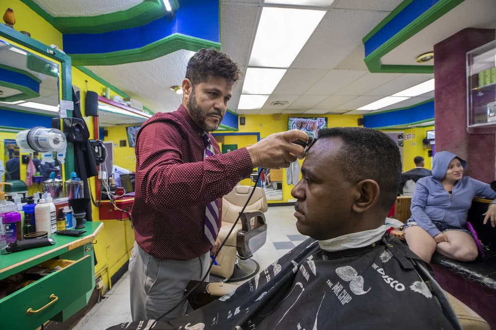 Cristino Acosta gives a trim to a customer at Canon's Place in Downtown Lynn. (Jesse Costa/WBUR)