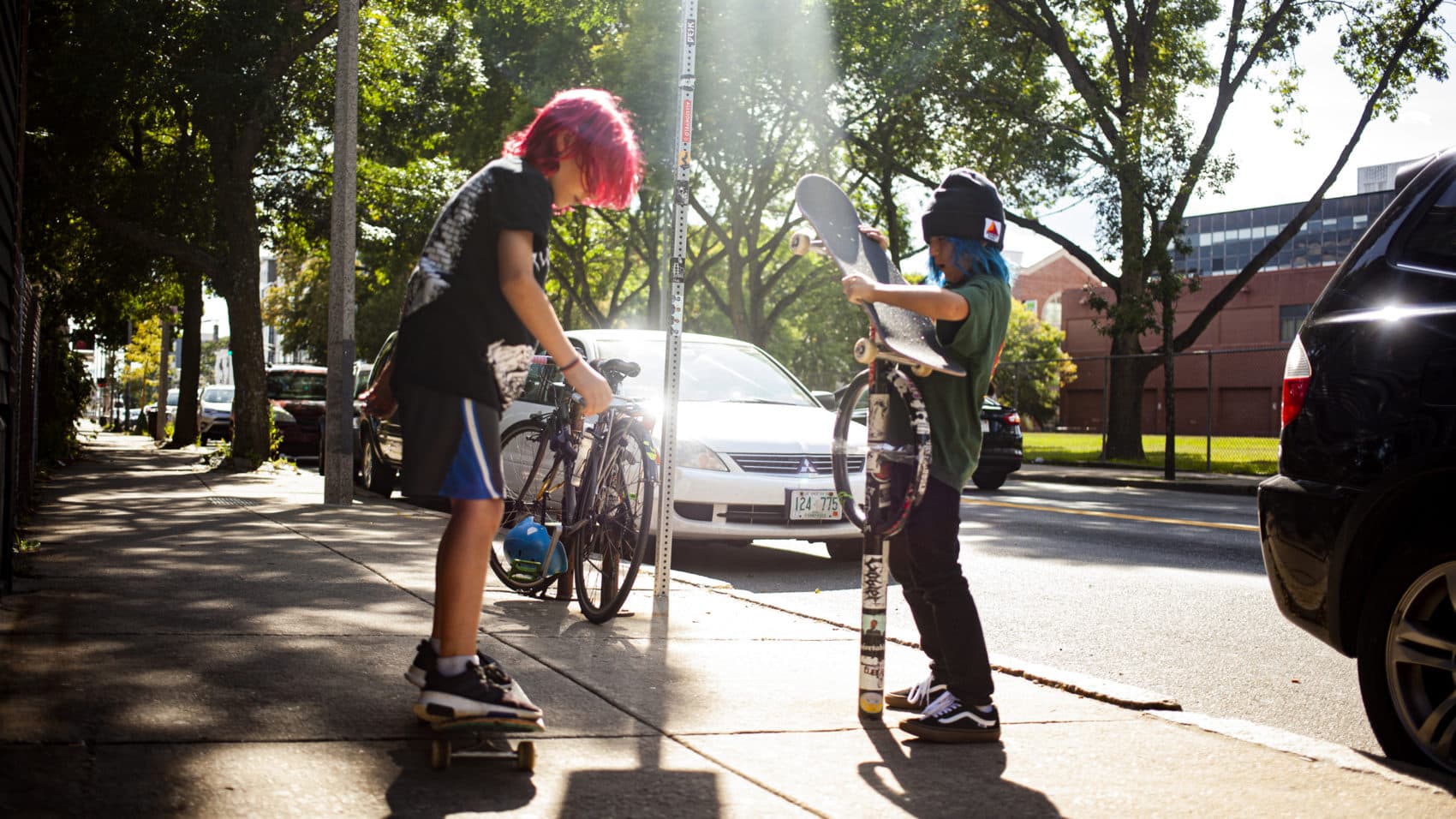 Matt Hiltz and Lincoln Zinzola play around, safely, with their skateboards on the sidewalk in Boston. (OJ Slaughter for WBUR)