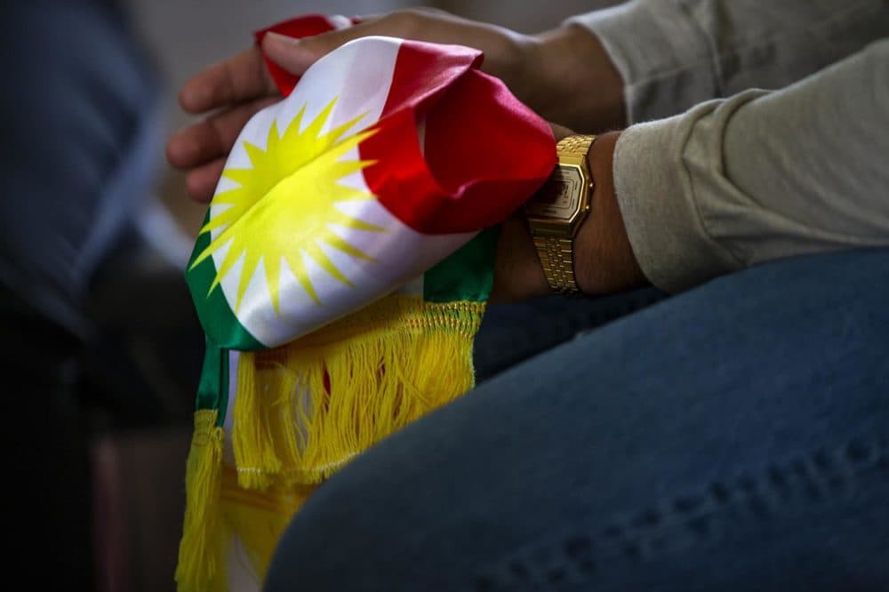 Amanj Omar, son of Delshad Osman, holds a Kurdish scarf in his hands. (Jesse Costa/WBUR)