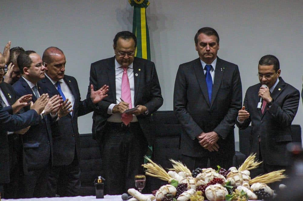 Brazilian congressman Silas Camara (pink tie) stands next to President Jair Bolsonaro during an evangelical service at the national Congress. (Paris Alston/WBUR)
