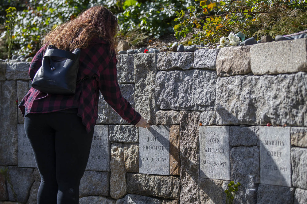 Brandi Mann traveled from Boaktown, New Brunswick, to leave a coin on the plaque of John Proctor, who was executed after defending his wife who was accused of witchcraft. He and his wife Martha were executed. His plaque sits at Proctor's Ledge, where historians believe 19 people were wrongfully executed. (Jesse Costa/WBUR)
