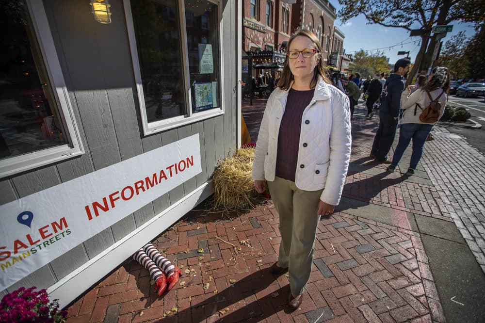Kate Fox, executive director at Destination Salem, stands in front of the information booth set up on the corner of Washington and Essex streets. (Jesse Costa/WBUR)