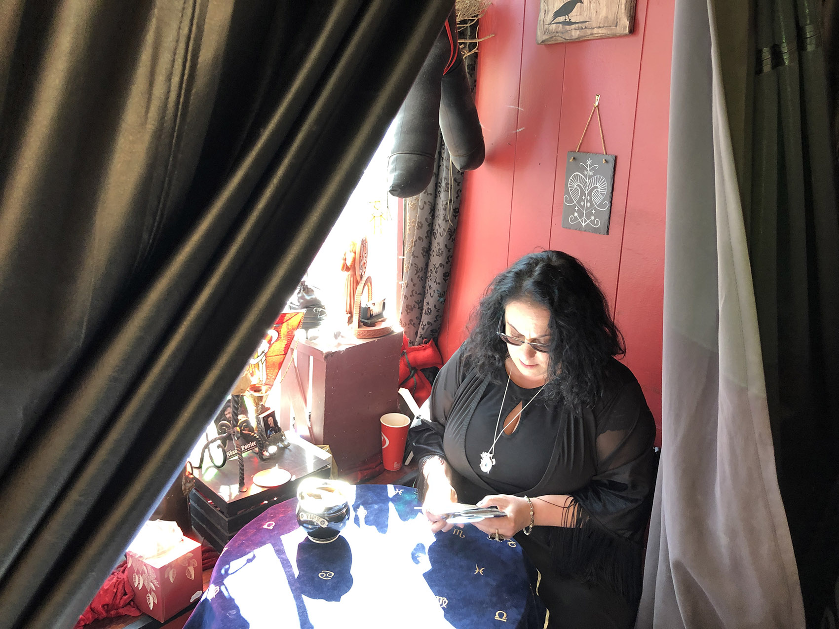 Salem witch and psychic Leanne Marrama sits in a corner at HEX: Old World Witchery in Salem. (Andrea Shea/WBUR)