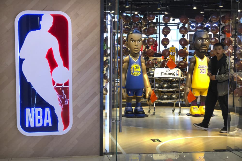 A man walks past statues of NBA players Stephen Curry of the Golden State Warriors, left, and Lebron James of the Los Angeles Lakers holding Chinese flags in the entrance of an NBA merchandise store in Beijing, Tuesday, Oct. 8, 2019. (Mark Schiefelbein/AP)