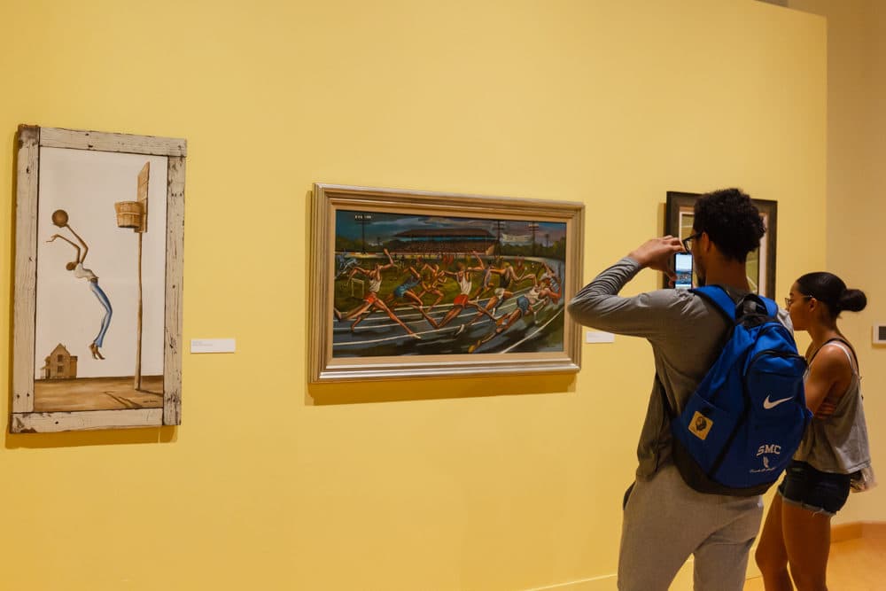 One visitor takes a photo of the &quot;Sugar Shack&quot; painting by the late artist Ernie Barnes. (Tonya Mosley/Here &amp; Now)
