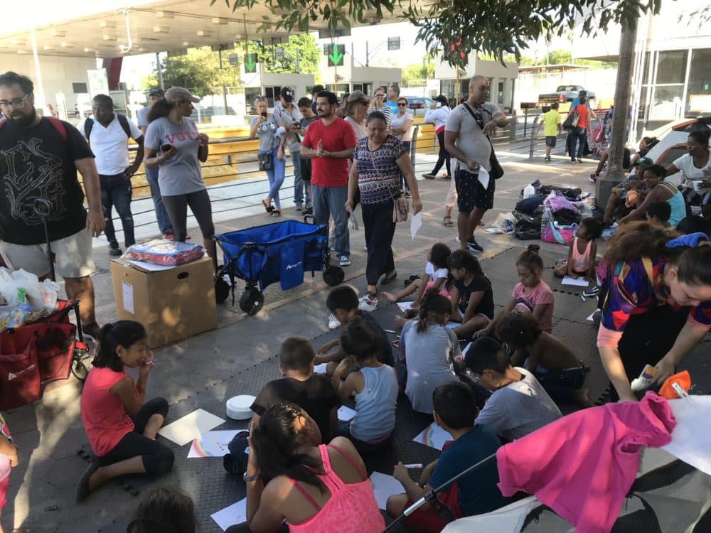 Children at the border encampment color and decorate plates during class on a Sunday morning, led by teachers from The Sidewalk School. (Andrea Asuaje/WBUR)