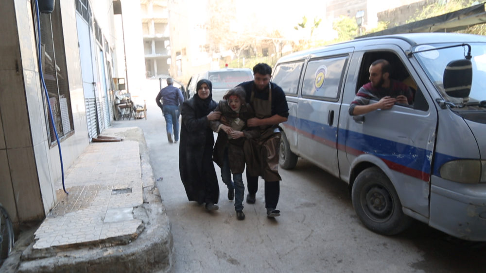 An injured girl is helped into the hospital for medical attention. (National Geographic)