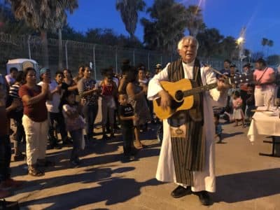 Father Bruce Nieli, a priest who from Austin, leads asylum seekers in song and prayer (Andrea Asuaje/WBUR)