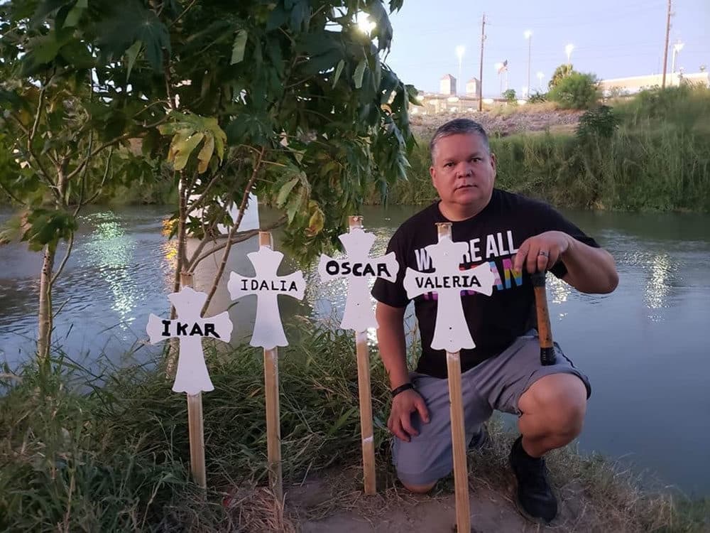 Mike Benavides kneels behind a makeshift grave for migrants who died while attempting to cross the Rio Grande (Credit Ann Finch)