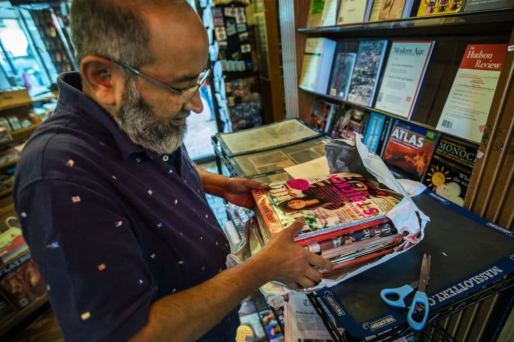 Mohammad Rahman unpacks some magazines to be restacked on the shelves. He has worked at Out of Town News for 22 years. (Jesse Costa/WBUR)