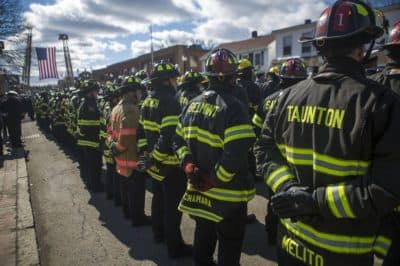 Lt. John Baccari carries the helmet of fallen Watertown firefighter Joseph Toscano as the funeral procession arrives at St. Patrick's Church Wednesday. Toscano collapsed while fighting a house fire on Friday. (Jesse Costa/WBUR)