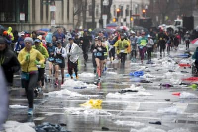 Marathoners run up a plastic poncho littered Hereford Street not far from the finish line. (Jesse Costa/WBUR)