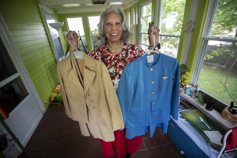 Sheila Nutt holds two outfits worn by Pan Am stewardesses in the '70s and '80s. (Jesse Costa/WBUR)