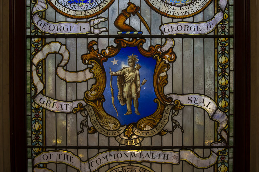An image of a glass-stained “Seal of the Commonwealth” located at the top of the grand staircase inside the State House. (Jesse Costa/WBUR)