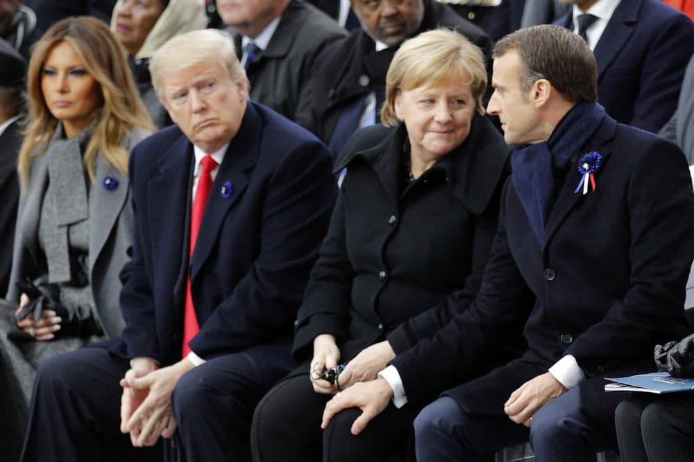 In this 2018 photo, President Trump watches French President Emmanuel Macron and German Chancellor Angela Merkel during ceremonies at the Arc de Triomphe in Paris. Trump officially notified the U.N. on Monday of his intention to withdraw the U.S. from the Paris Climate Agreement. France and Germany remain in the agreement. (Francois Mori/AP)