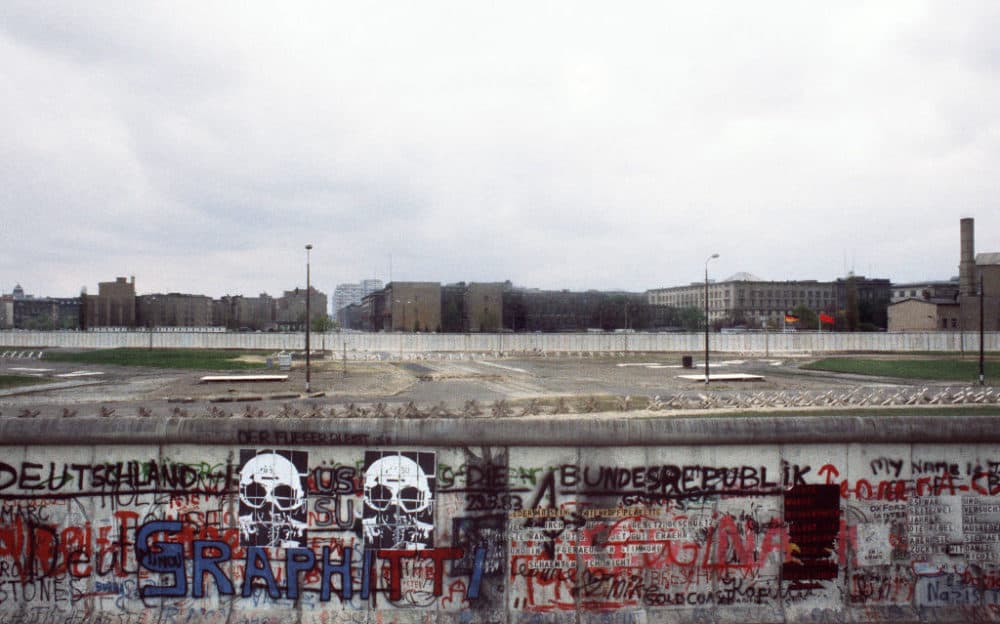 Various graffiti are painted on the Berlin Wall on the West Berlin side in April 1984 while East German and Soviet flags (R) fly on the other side of the East Berlin no-mans-land spiked with anti-tanks traps. (Joel Robine/AFP/Getty Images) 
