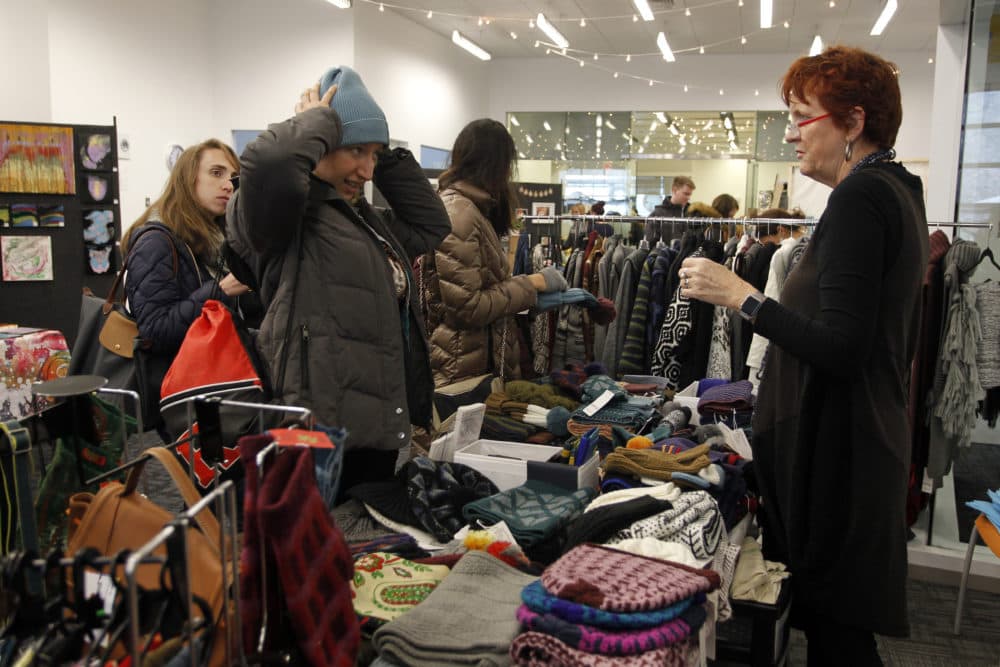 A holiday shopper tries on a winter hat at the Allston-Brighton Winter Market in 2017. (Courtesy of Stew Milne)