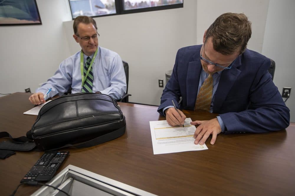 After the inspection was complete, Michael Dundas signs a copy of the inspection acknowledgment. (Jesse Costa/WBUR)