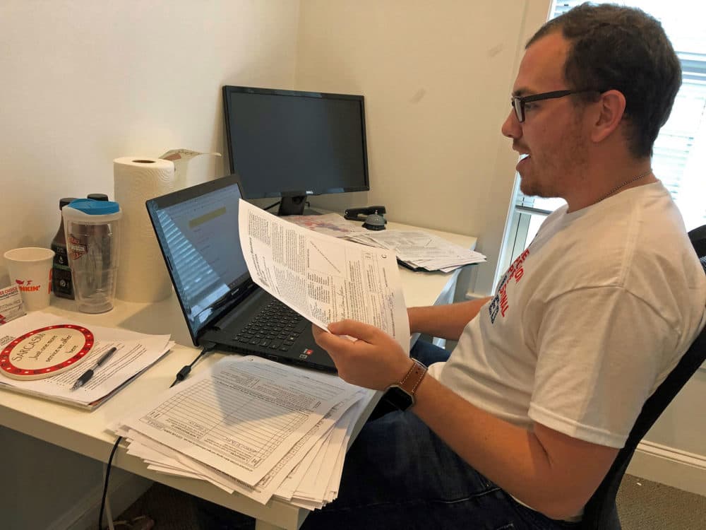 Matt Frentz sorts petitions supporting a possible ballot measure that would bring ranked-choice voting to Massachusetts. (Callum Borchers/WBUR)