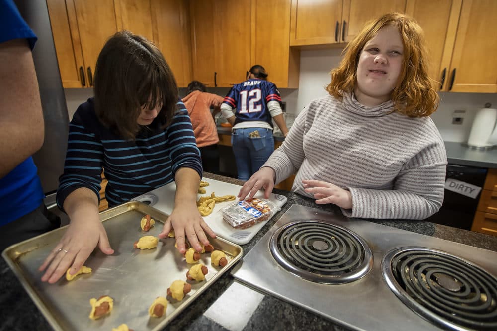 Haley Valente, left, and Sophie Brown wrap miniature hot dogs with crescent dough making pigs in a blanket for their Super Bowl watch party organized by the students of the College Success program at the Perkins School for the Blind. (Jesse Costa/WBUR)