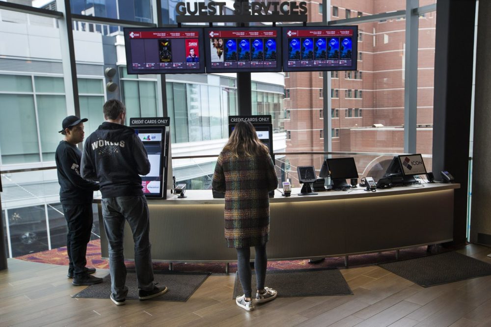 Two people buy tickets at the self-serve kiosk in the lobby of the ShowPlace ICON in the Seaport. (Jesse Costa/WBUR)