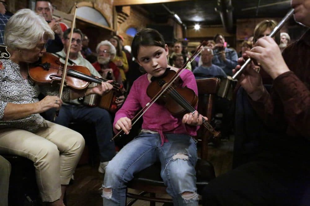 Theresa Stokinger, 8, plays the fiddle during an Irish music session at the Green Briar pub in Brighton. (Hadley Green for WBUR)