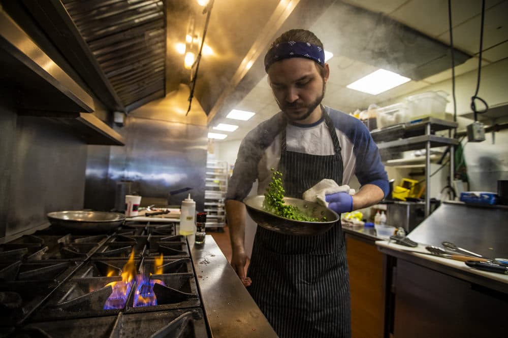 Chef David Ferragamo tosses a pan of sauteed peas in a pan. (Jesse Costa/WBUR)