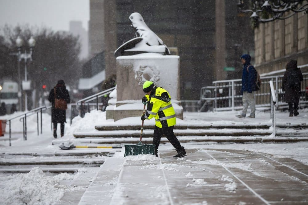 A worker clears snow from the steps of the Boston Public Library during the morning snowstorm. (Jesse Costa/WBUR)