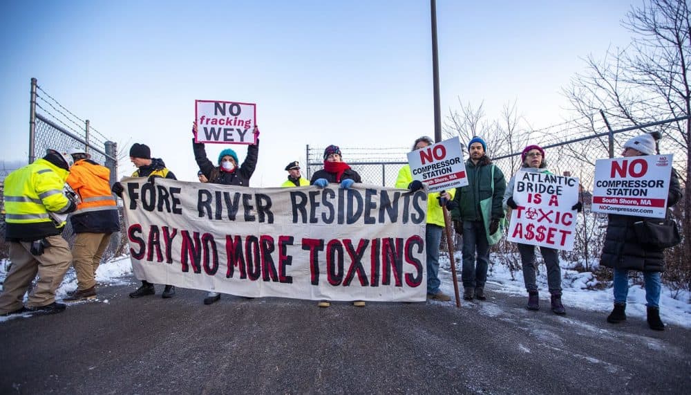 Protesters stand in front of the gate of the proposed compressor building site on the Fore River in Weymouth. (Jesse Costa/WBUR)